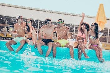 Young teens sitting on the edge of pool while splashing water